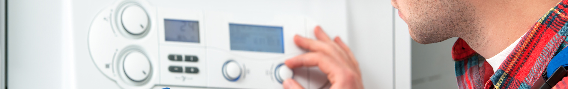 close up of man turning a dial on a thermostat boiler control for Guy Crabb Heating